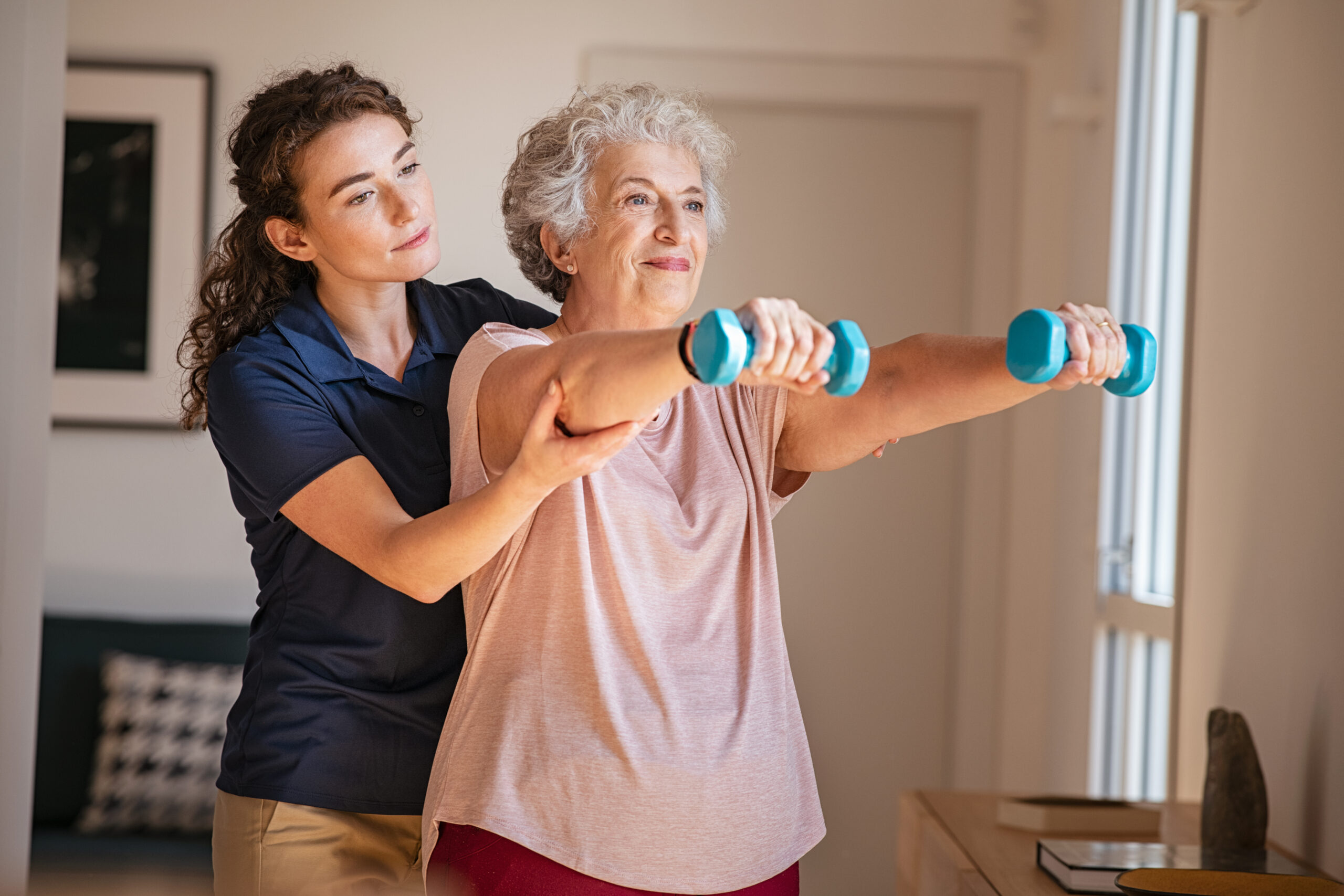 Old,Woman,Training,With,Physiotherapist,Using,Dumbbells,At,Home.,Therapist Dallas Home Care Agency